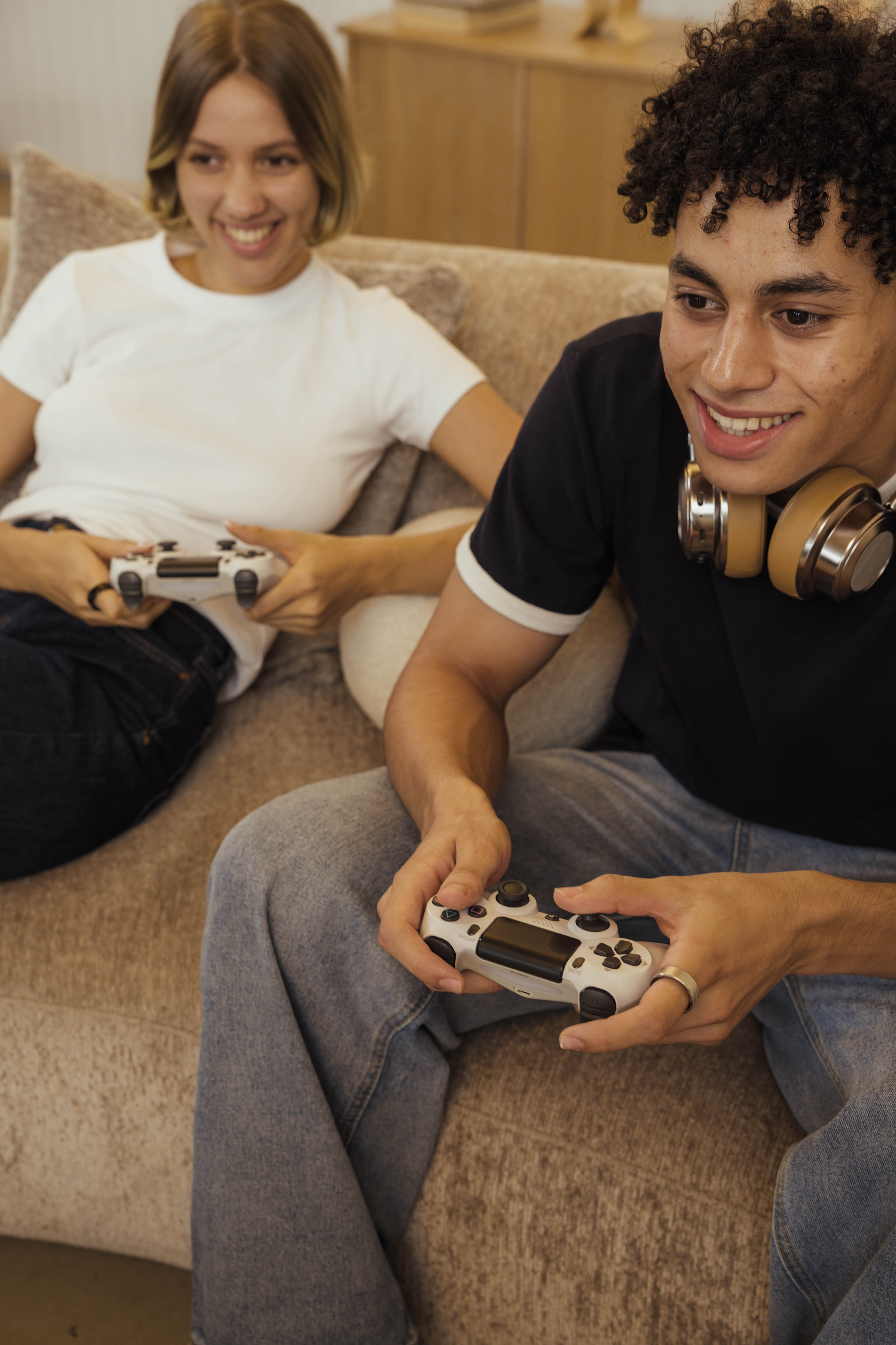 Two friends laughing together on a couch, one wearing the USAY Ring while holding a game controller